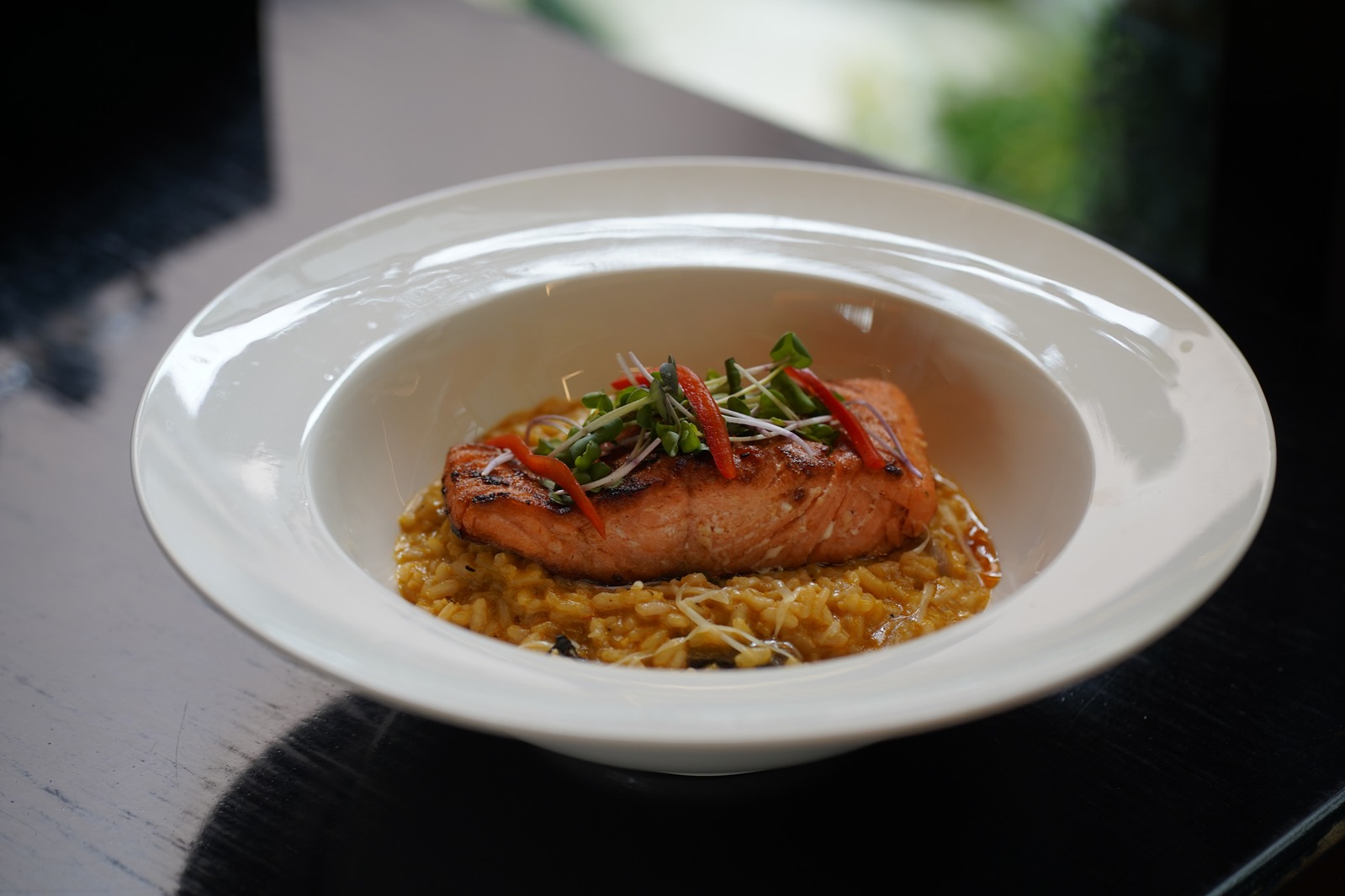 Salmón dorado servido sobre arroz cremoso en Esquinita Inka